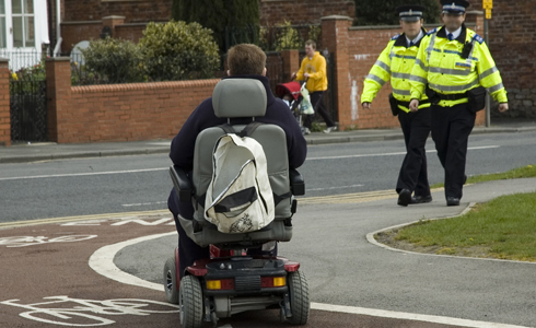 Two policemen and a wheelchair user in a street